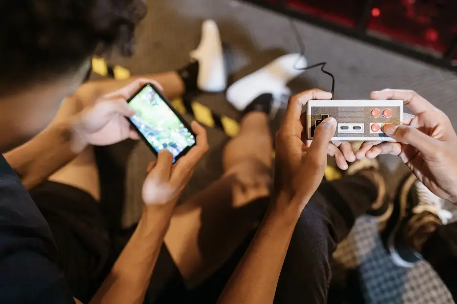 Two people playing on a phone and a vintage game